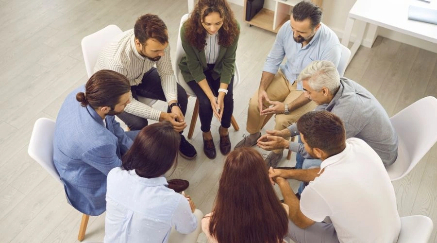 Image of men and women sitting in a circle attending rehab