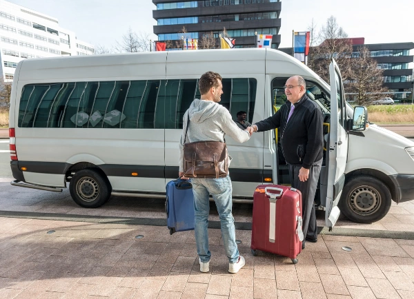 Image of male taxi driver shaking hands with man by van at Airport - Free Transportation to Rehab for Clients Image of male van driver shaking hands with man he is picking up at the Airport - Free Transportation to Rehab for Clients