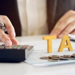 Image of a man's hand on a calculator with the word TAX next to it - Is Rehab Tax Deductible