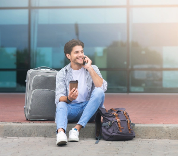 Smiling man talking On cellphone and waiting to be picked up at the Airport