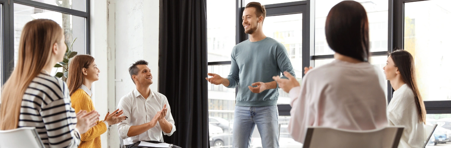 Image of a man standing and sharing at an AA meeting - AA Meeting Topics - Ingrained Recovery