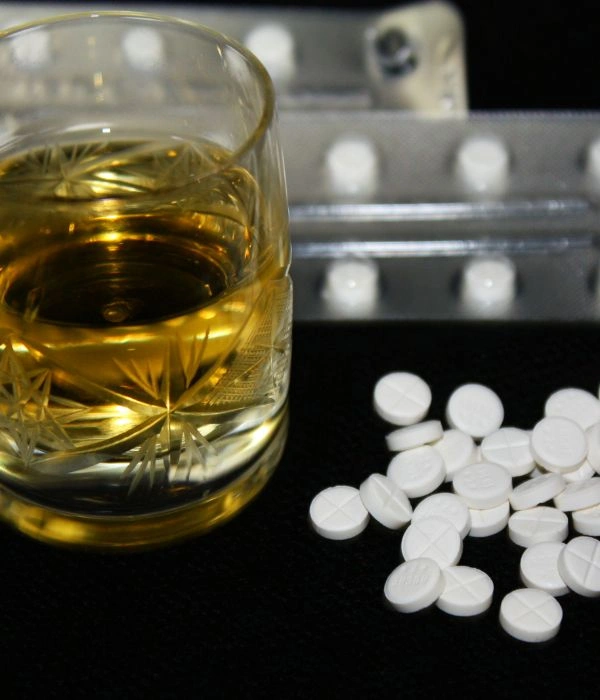 Image of a glass of alcohol on table besides Xanax pills - Dangers of Mixing Xanax and Alcohol