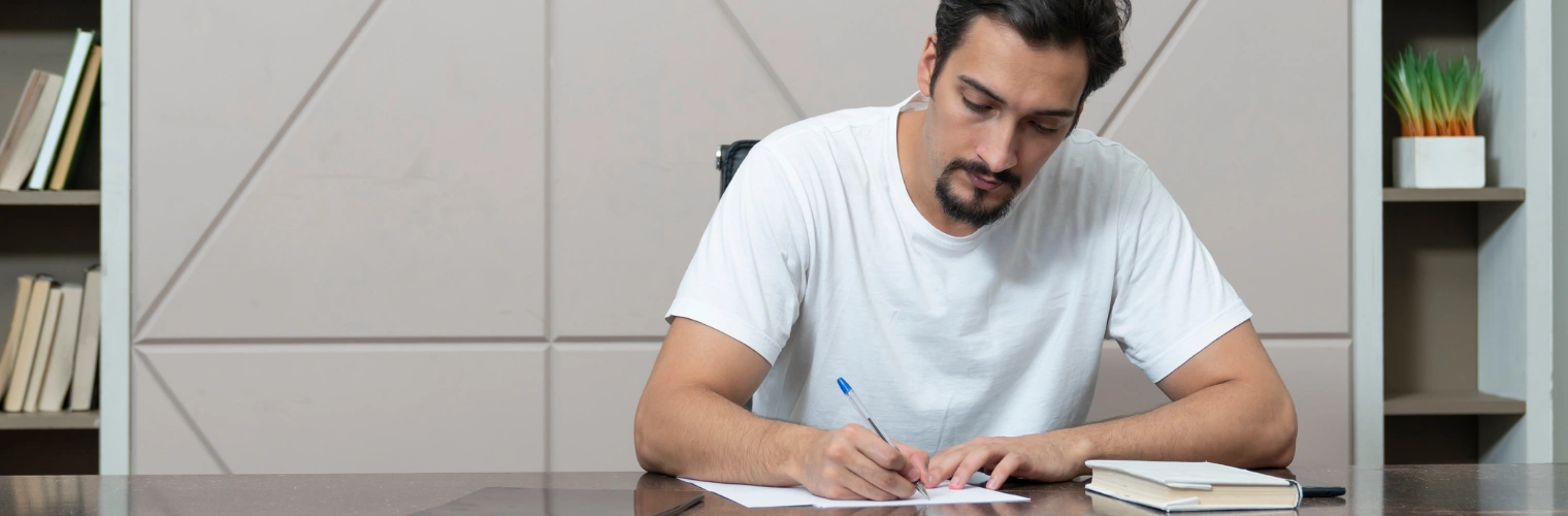 Image of a man sitting at a desk making his amends list
