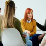 Image of men and women sitting in a circle at an AA meeting - What is a Sponsor in AA - Ingrained Recovery