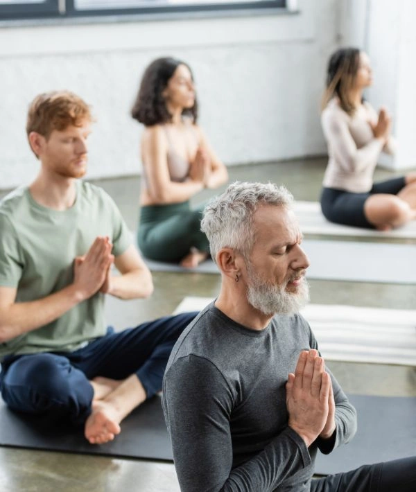 12-Step Recovery Yoga at Ingrained Recovery Image of men and women on their yoga mats with legs crossed, engaged in the Prayer Yoga Pose - 12-Step Recovery Yoga at Ingrained Recovery