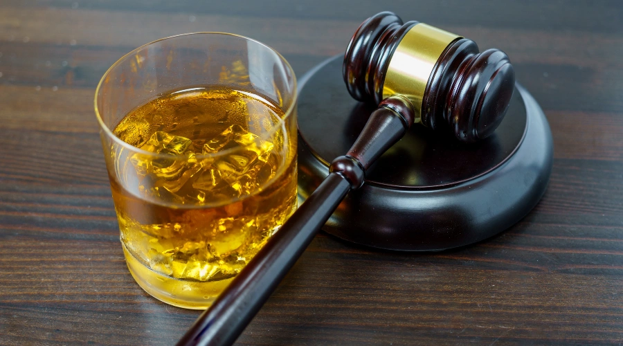 Image of a glass of whiskey next to a gavel on a table - Legal and workplace consequences of drinking on the job