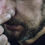Image of a close-up of a man's face with his fingers wiping his nose - What Is Cocaine Drip - Ingrained Recovery