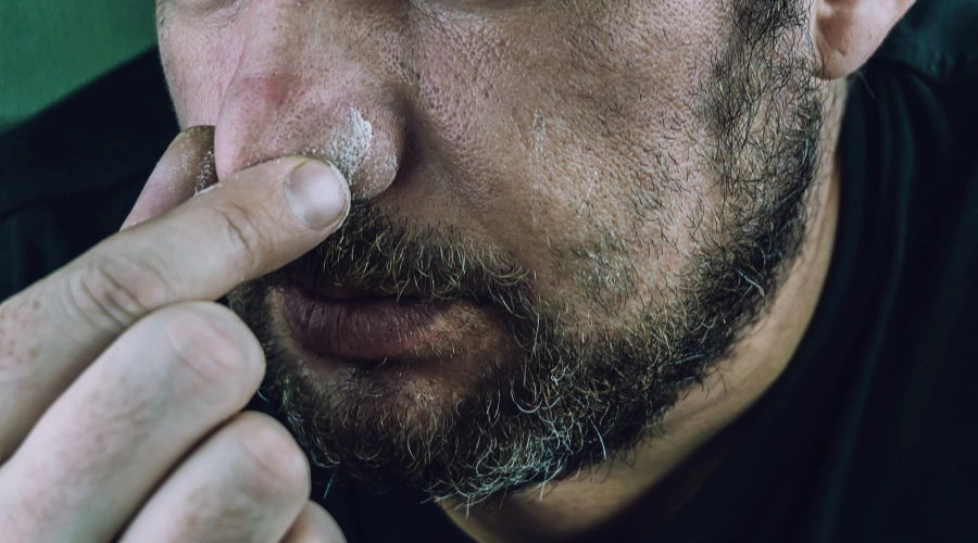 Image of a close-up of a man's face with his fingers wiping his nose - What Is Cocaine Drip - Ingrained Recovery