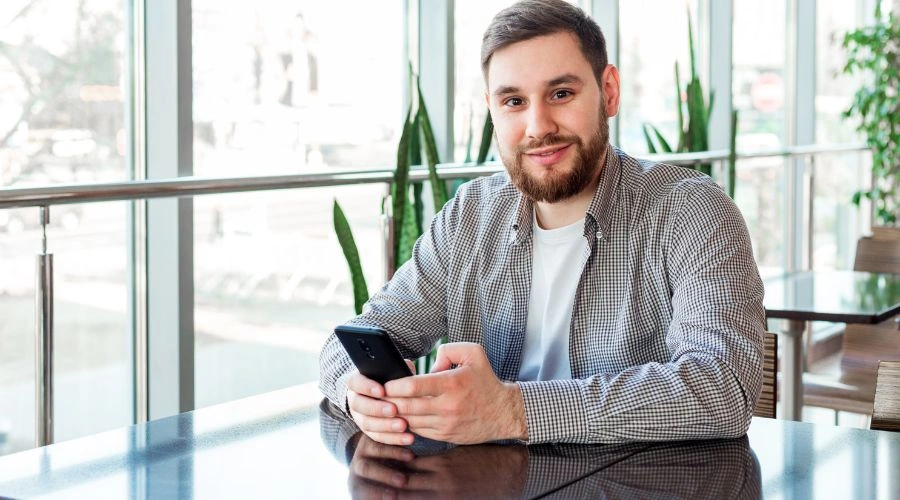 Image of a man sitting with this phone at a rebab center - Can You Have Your Phone in Rehab - Ingrained Recovery