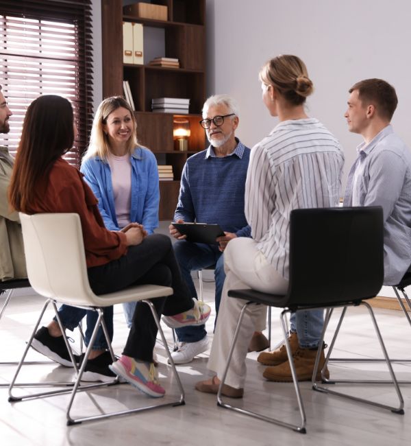 Image of men and women sitting in a circle at a recovery meeting, building support and long-term sobriety