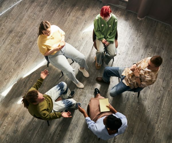 Image of Group therapy session with participants seated in a circle Image of an AA Group therapy session with men and women seated in a circle