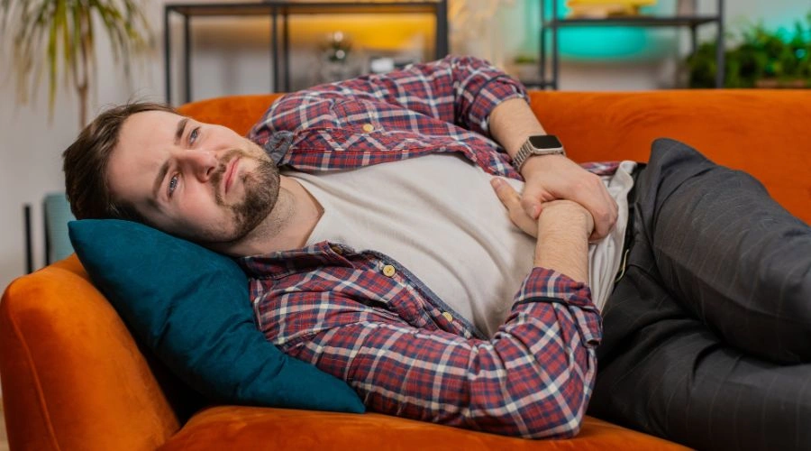 Image of Man clutching his stomach in pain from alcohol-related peptic ulcers