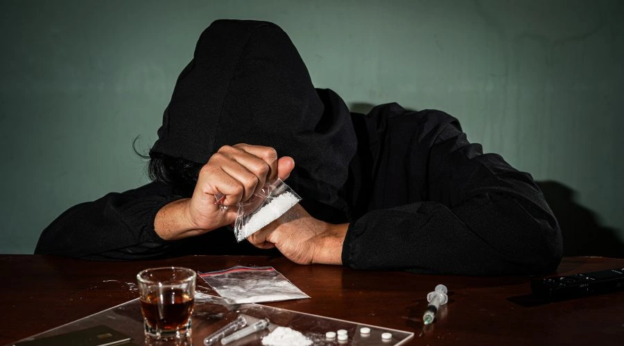 Image of a tired man holding a small cocaine packet, showing exhaustion and the physical toll of cocaine comedown