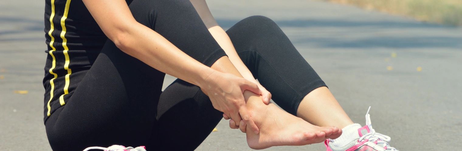 Image of young female athlete sitting with an injured ankle