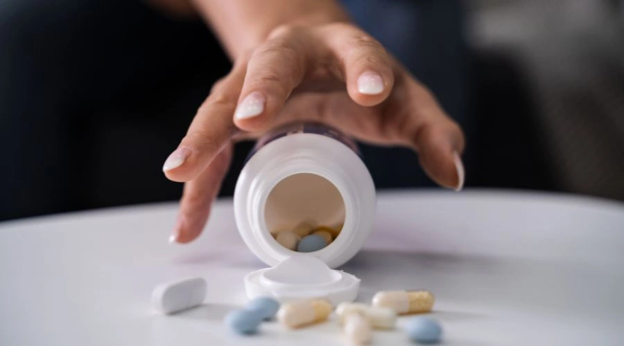 Man trying to grab Roxies tablets on a table, depicting opioid use and addiction risk