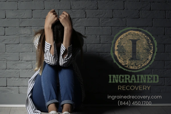 Image of a woman sitting on the floor in front of a wall - Relapse Prevention Worksheet Resources - Ingrained Recovery