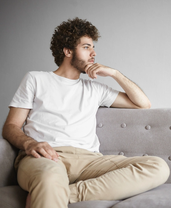 Image of a young adult male sitting alone in his room