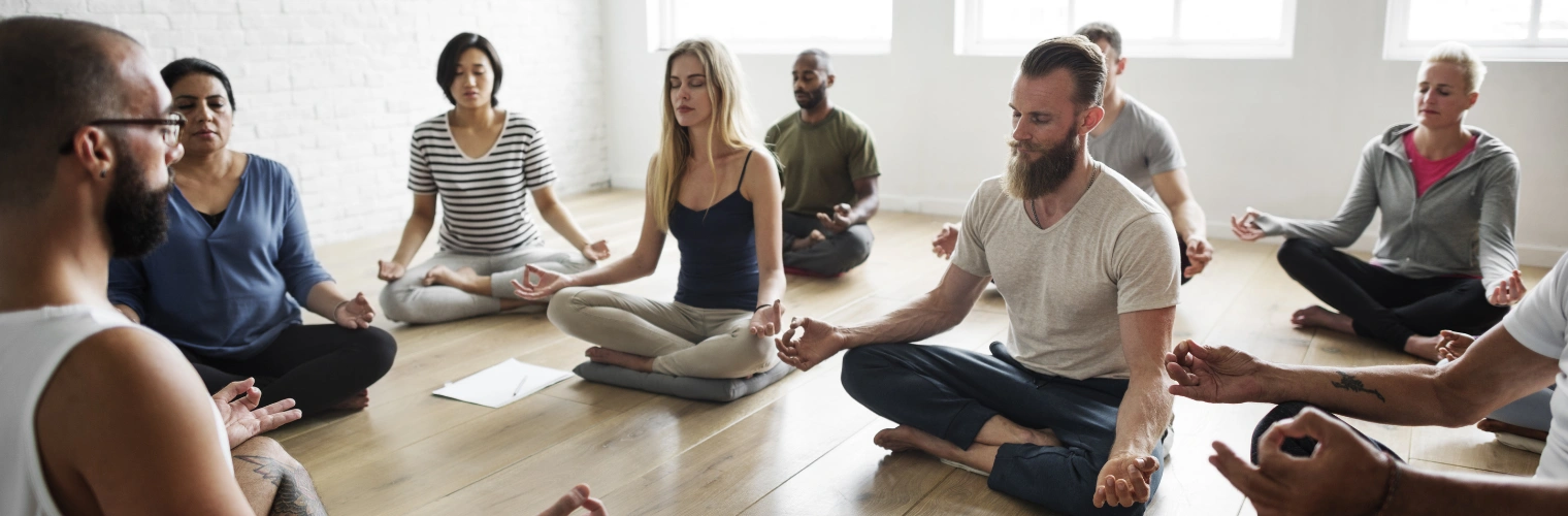 Image of addiction recovery group practicing mindfulness breathing exercises with therapist guidance during group therapy Image of embers of an addiction recovery group practicing mindfulness breathing and yoga exercises with therapist guidance during group therapy