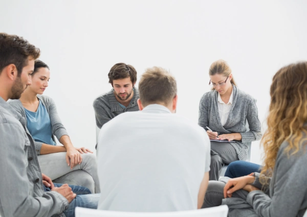 Image of men and women sitting in a circle at an AA meeting reflecting on Alcoholics Anonymous Step 4