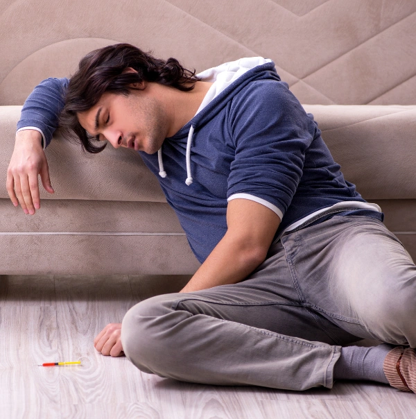 Image of a man sitting on the floor feeling anxious and overwhelmed during a marijuana intoxication episode Image of a man sitting on the floor feeling anxious and overwhelmed during a marijuana intoxication episode