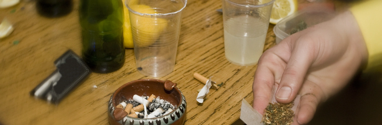 Image of a person mixing alcohol and cannabis representing the risk factors that can make a greening out episode last longer or feel worse Image of a person mixing alcohol and cannabis representing the risk factors that can make a greening out episode last longer or feel worse