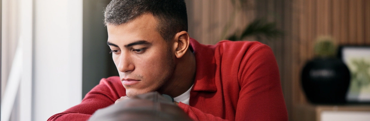 Image of a person pausing thoughtfully near a window Image of a person pausing thoughtfully near a window