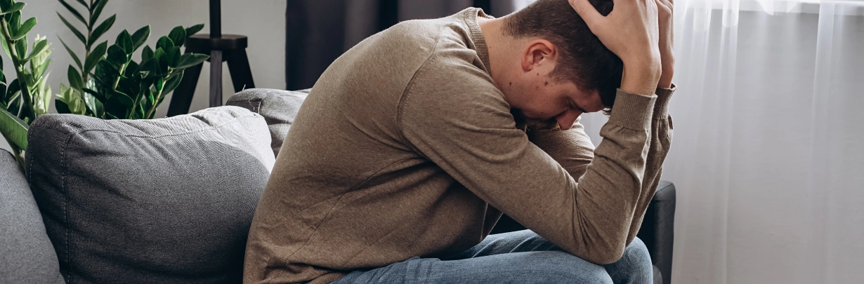 Image of a person sitting alone looking distressed on a couch Kratom and Alcohol: Risks of Mixing Them