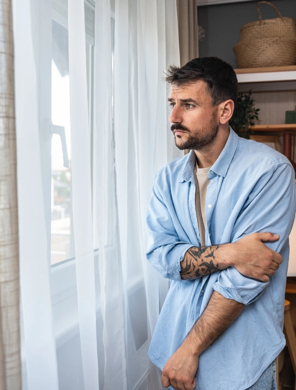 Image of a person sitting quietly in thought near a window at home Image of a person sitting quietly in thought near a window at home