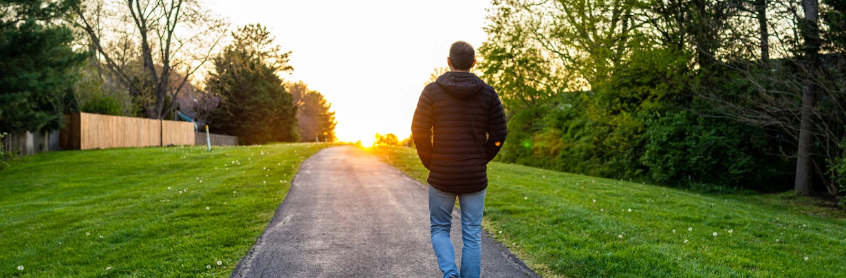 Image of a person walking outdoors in early morning sunlight Image of a person walking outdoors in early morning sunlight