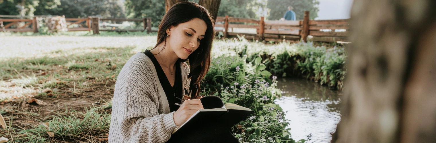 Image of a person journaling outdoors on a porch surrounded by greenery Image of a person journaling outdoors on a porch surrounded by greenery shows the concept of woodland therapy for addiction recovery