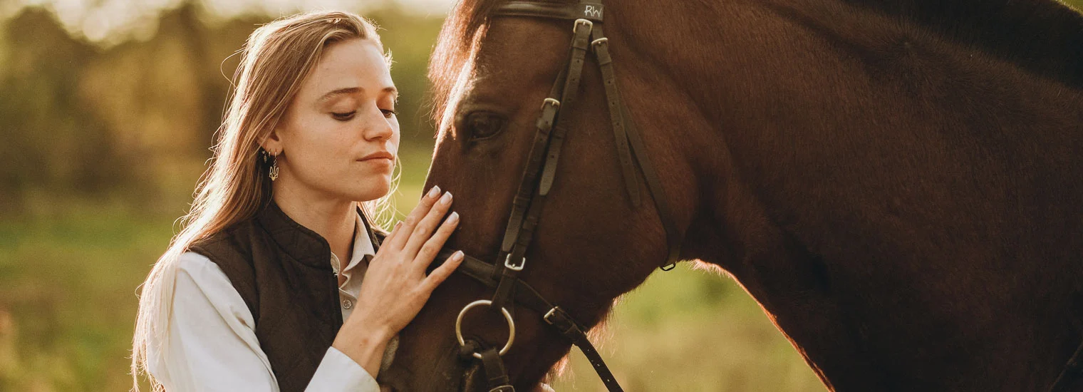 Image of a woman gently touching a brown horse during an equine-assisted therapy session Image of a woman gently touching a brown horse during an equine-assisted therapy session